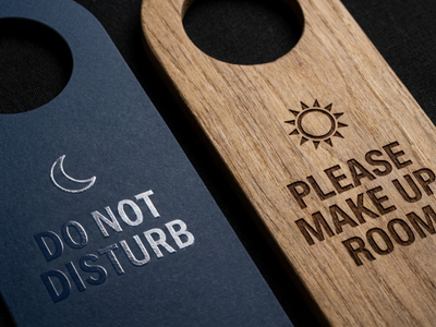 Custom hotel door hangers, one blue with a moon icon and "Do Not Disturb" text, and one wooden with a sun icon and "Please Make Up Room" text